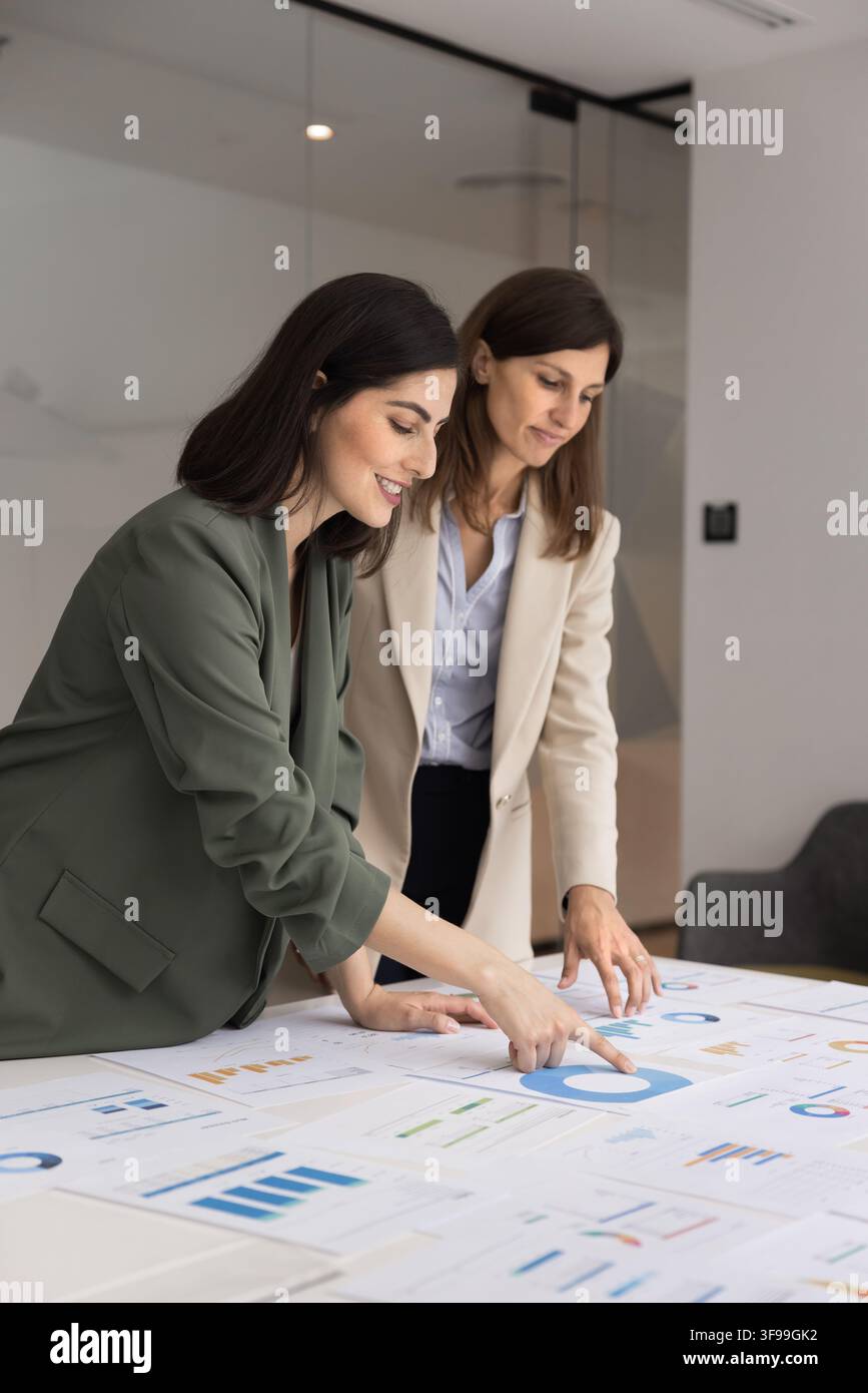 Experienced female analyst training colleague on data visualization at workplace Stock Photo