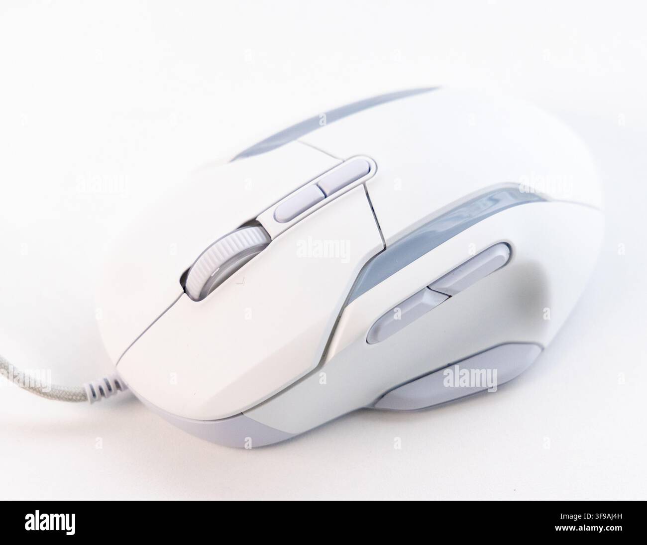 A white and grey wired computer mouse rests on a plain surface Stock Photo