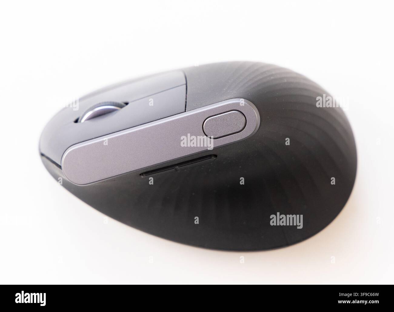 A black ergonomic wireless computer mouse rests on a white background Stock Photo