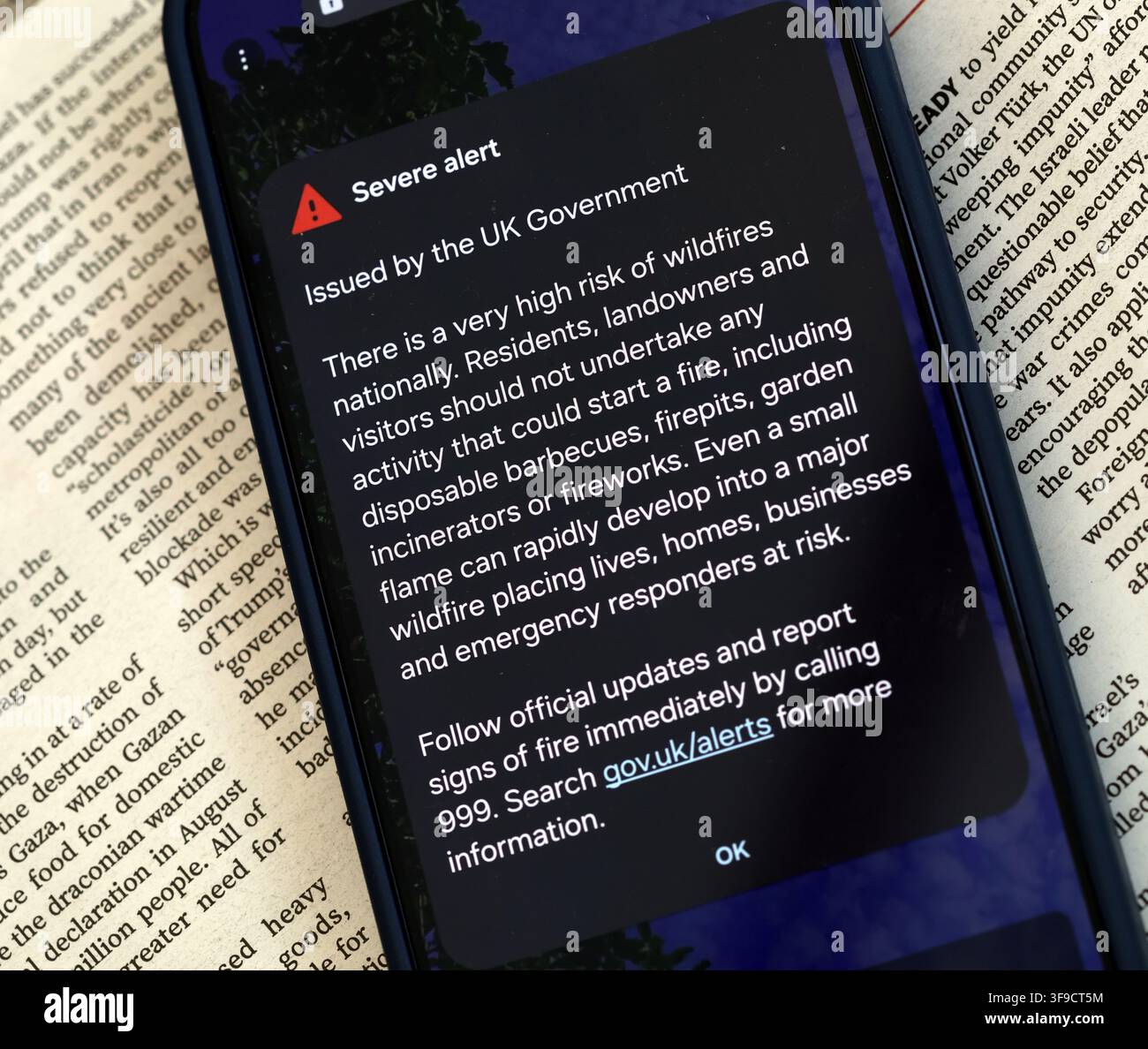 Smartphone showing the 14 August 2026 UK wildfire Emergency Alert, urging people to avoid barbecues, firepits, incinerators and fireworks. Stock Photo