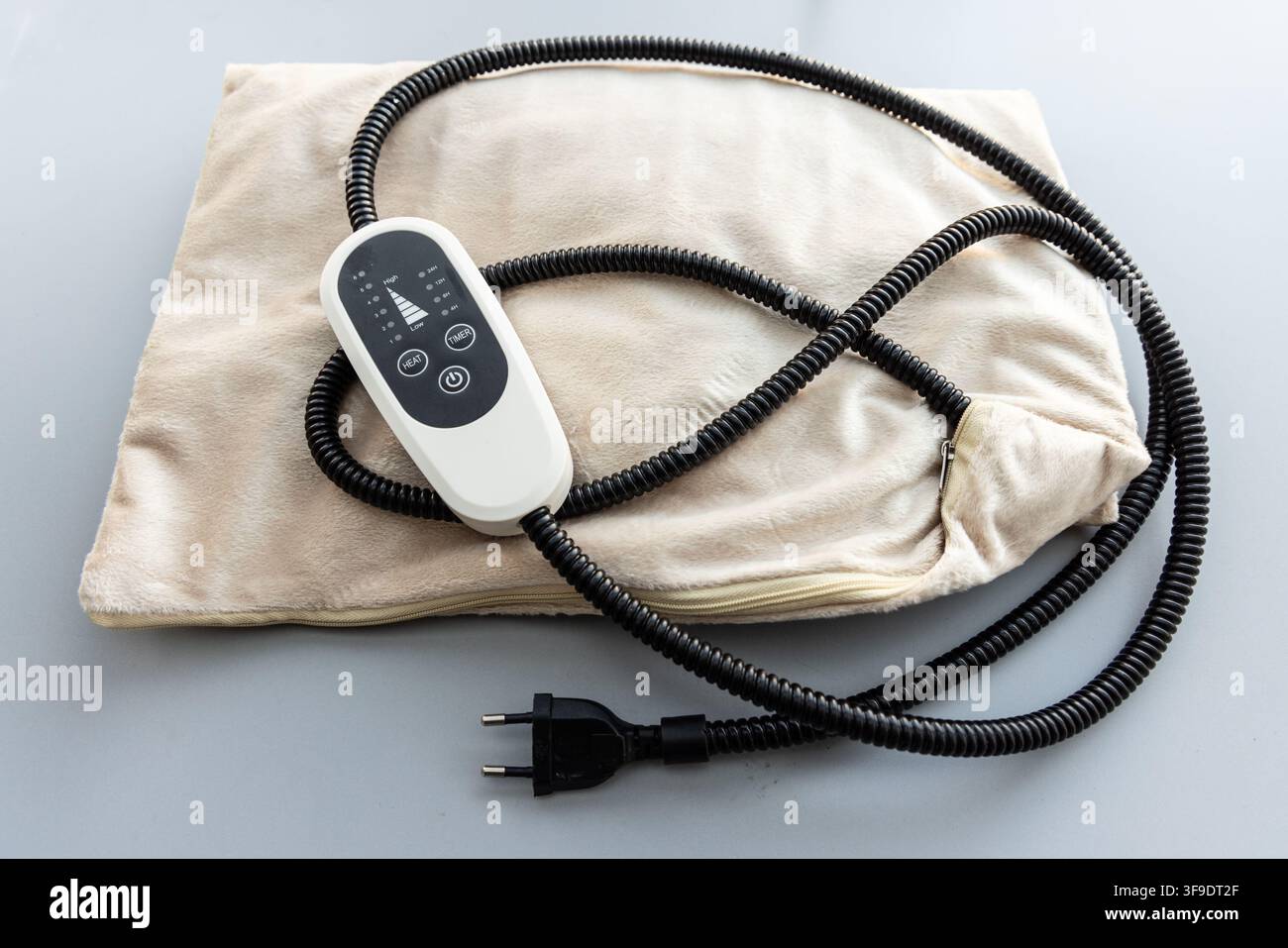 A fluffy beige electric heating pad with a digital controller is shown Stock Photo