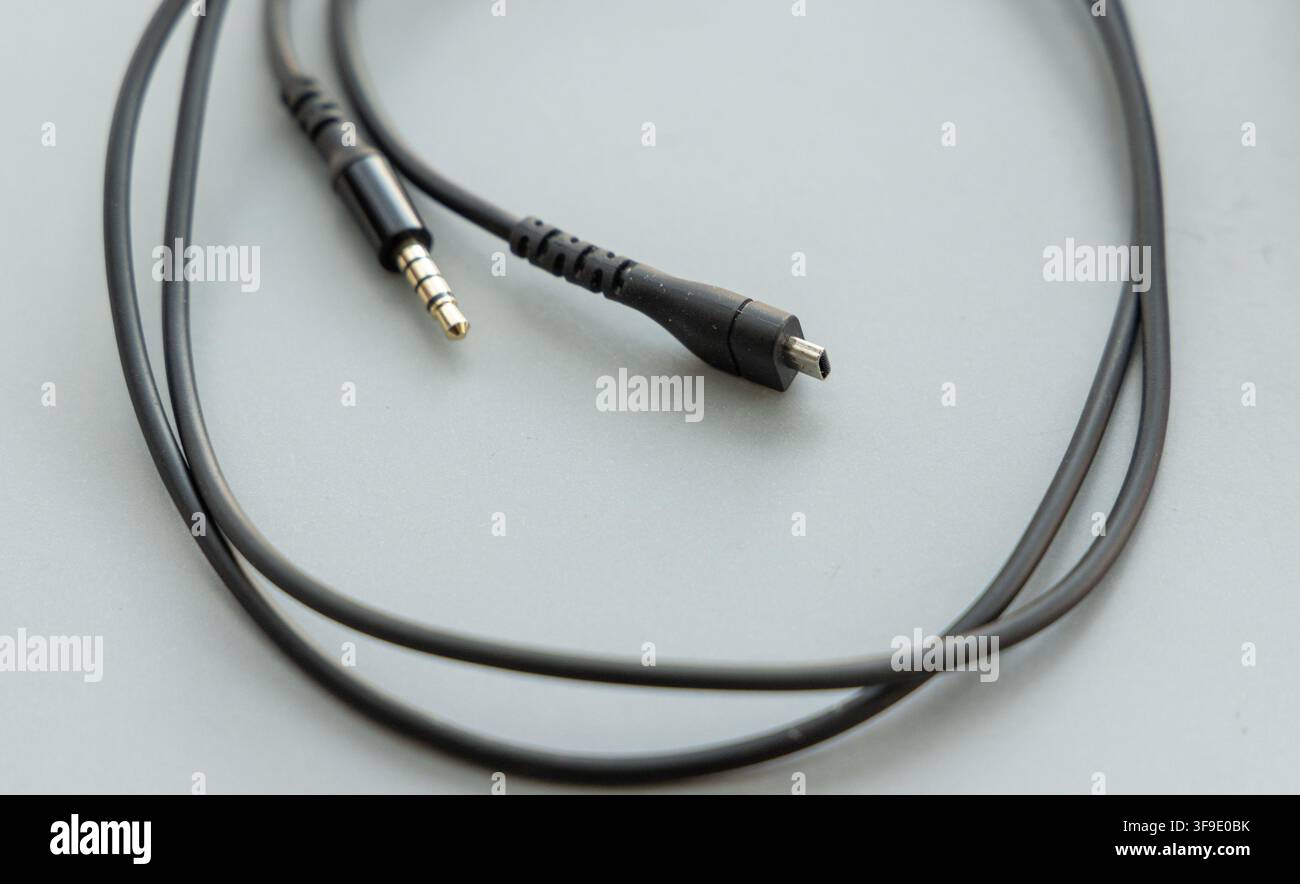 A black audio cable rests on a light gray background Stock Photo