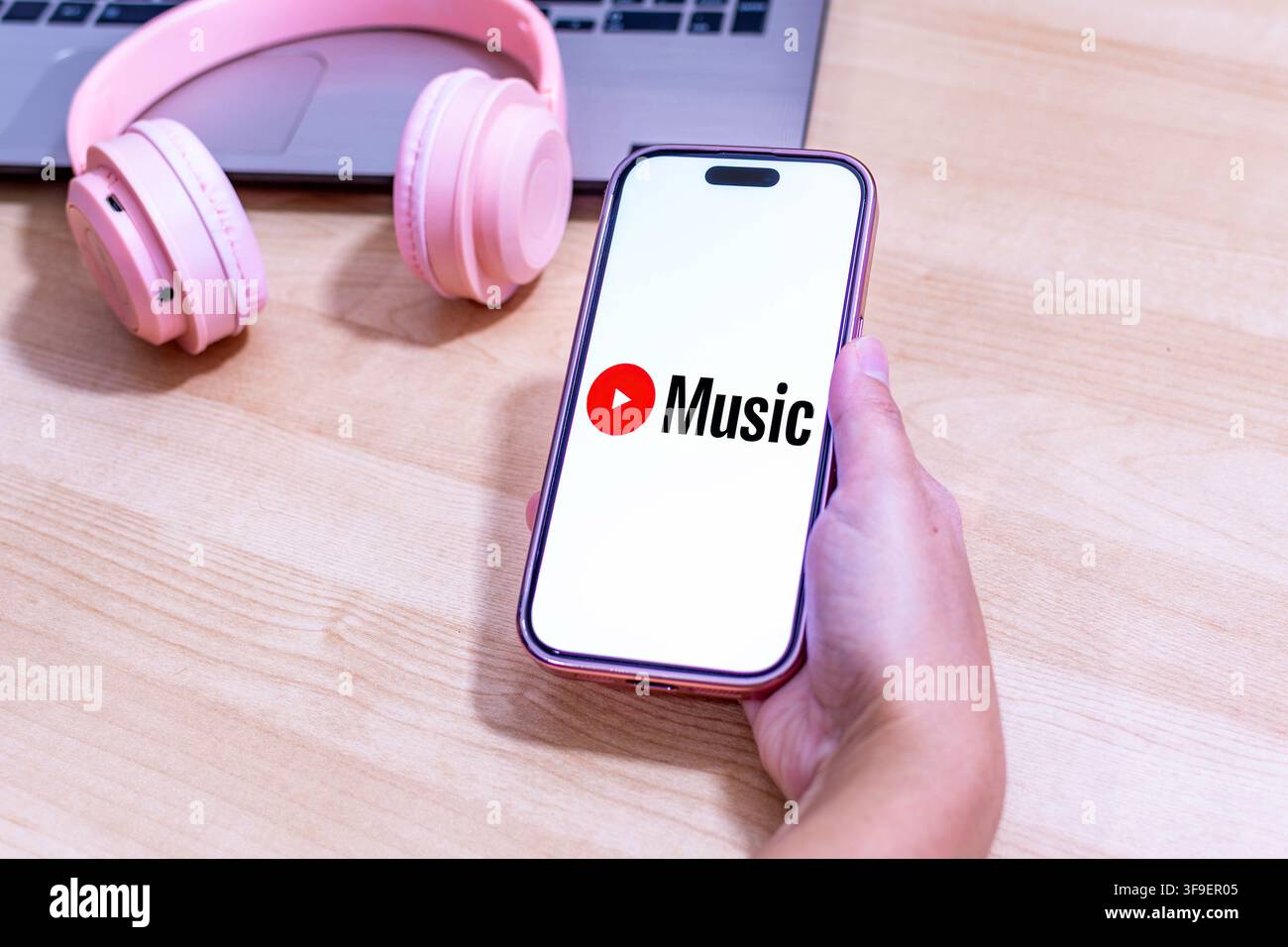 Hand holding an iPhone with the Youtube Music app logo. Stock Photo