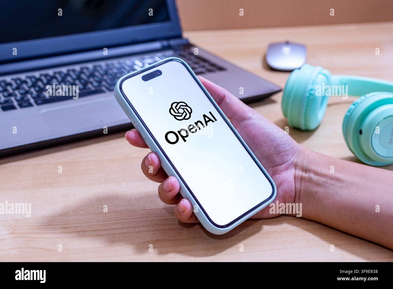 Hand holding an iPhone with the OpenAI app logo. Stock Photo