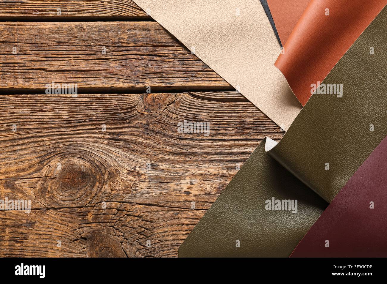 Various colored leather samples on a rustic wooden background, material selection and craftsmanship Stock Photo