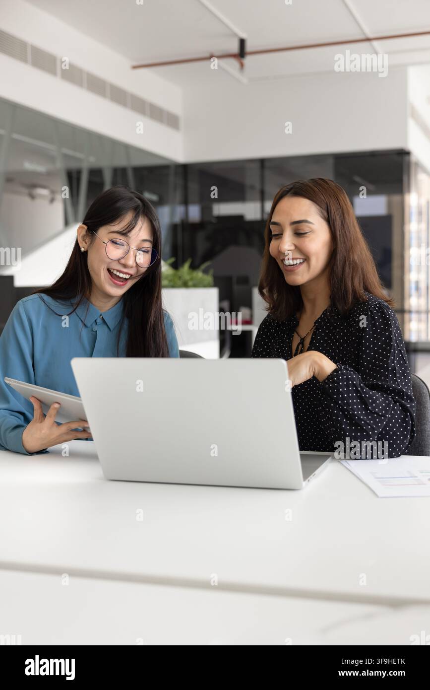Women colleagues working on joint task using tablet and laptop Stock Photo