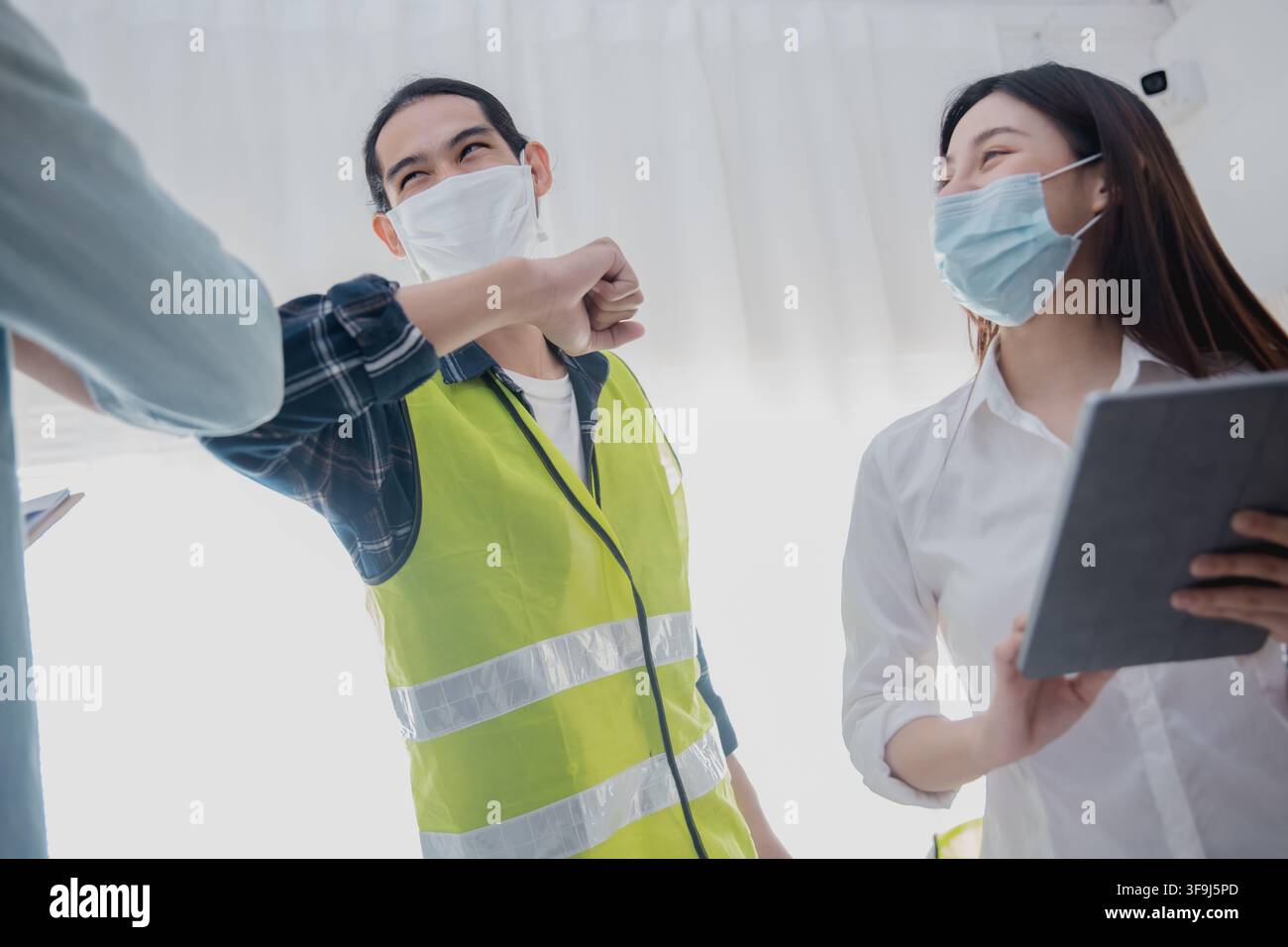 Engineers greeting with elbow bump while wearing face mask during construction meeting Stock Photo