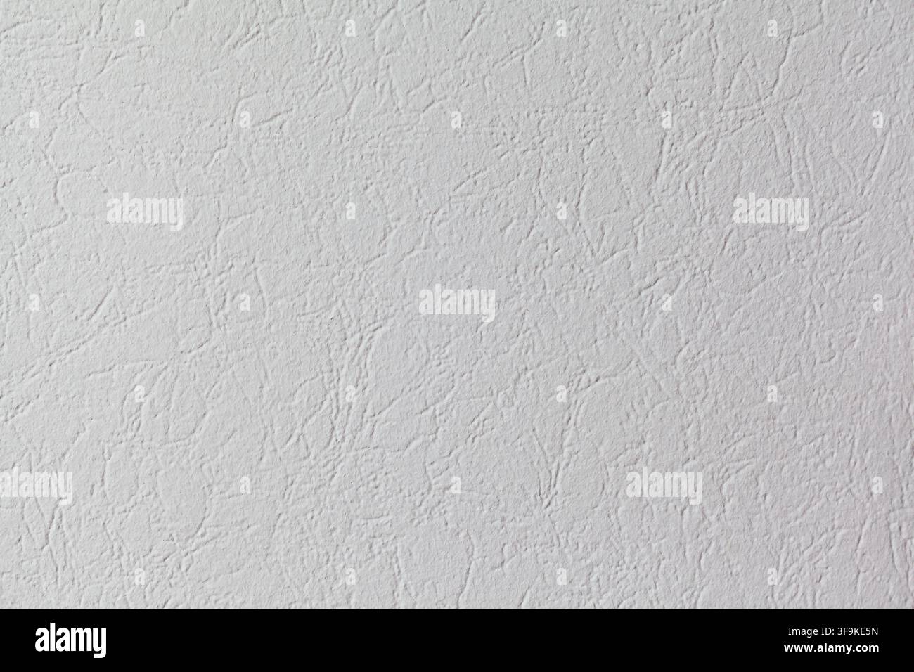 Textured white wall surface with subtle patterns and variations in light, ideal for backgrounds and design projects Stock Photo