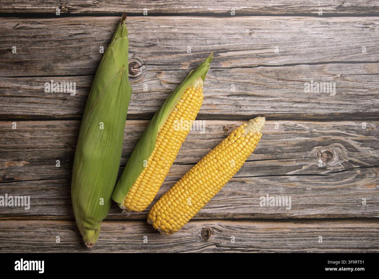 Fresh corn cobs on flat wooden background. Stock Photo