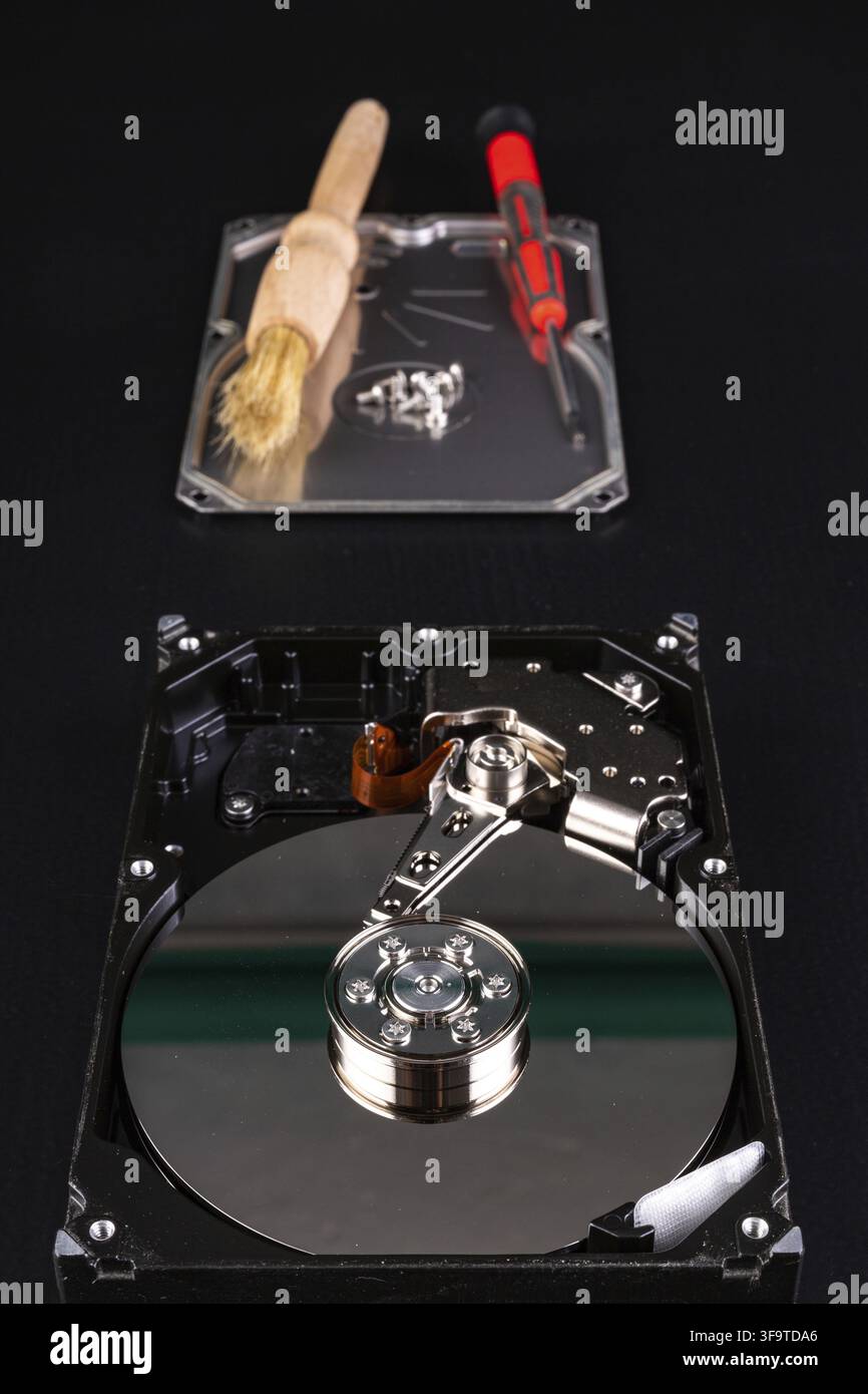 Cleaning the hard disk with a brush. Vacuuming old disk data on your computer. Dark background Stock Photo