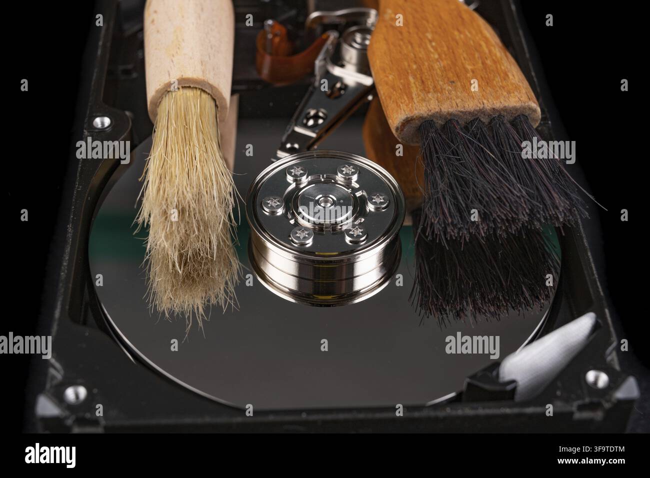 Cleaning the hard disk with a brush. Vacuuming old disk data on your computer. Dark background Stock Photo