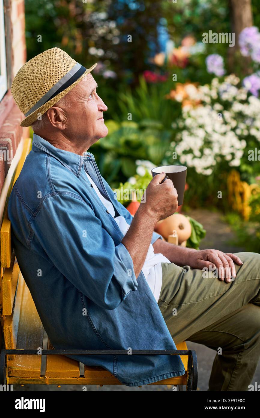 Senior Man Drinking Coffee on Bench in Garden Stock Photo