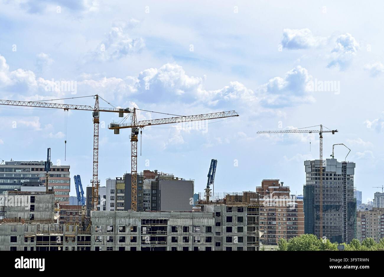 Urban Development: Tower Cranes Constructing Modern High-Rise Buildings Against Cloudy Skyline Stock Photo