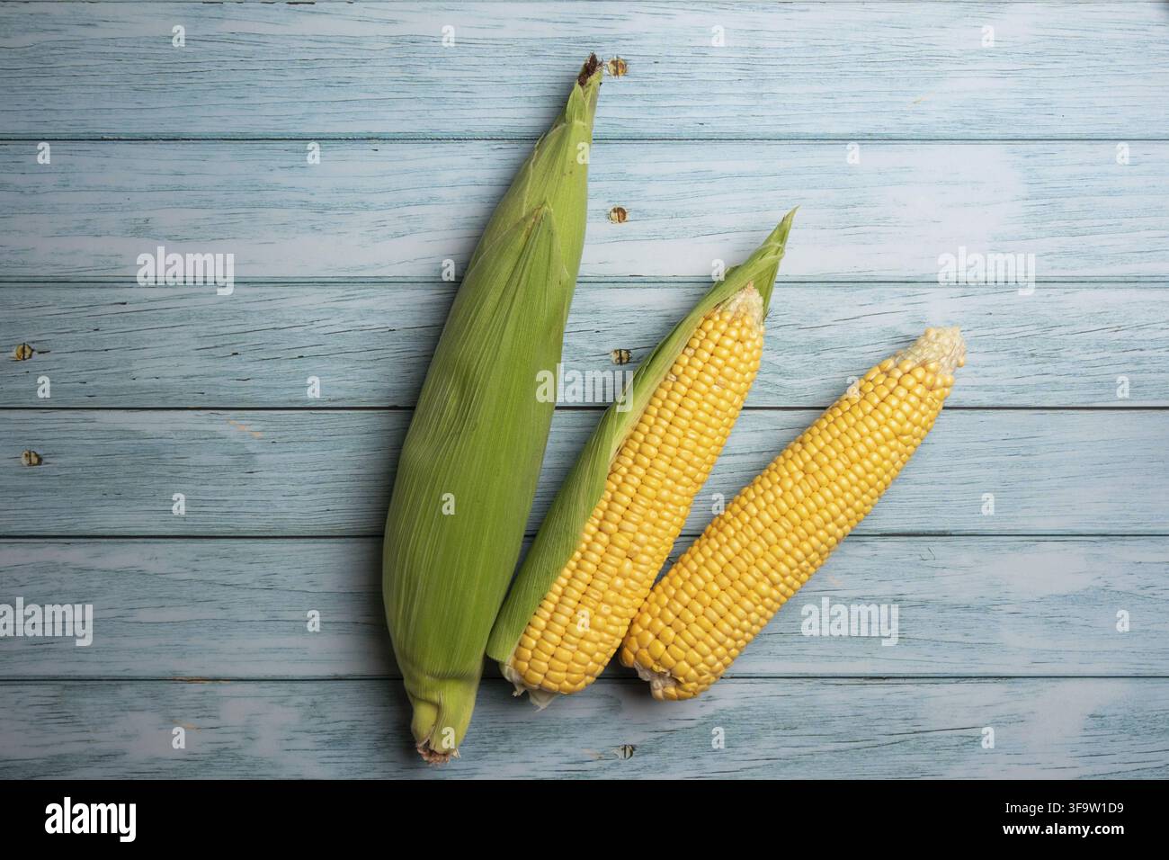 Fresh corn cobs on flat wooden background. Stock Photo