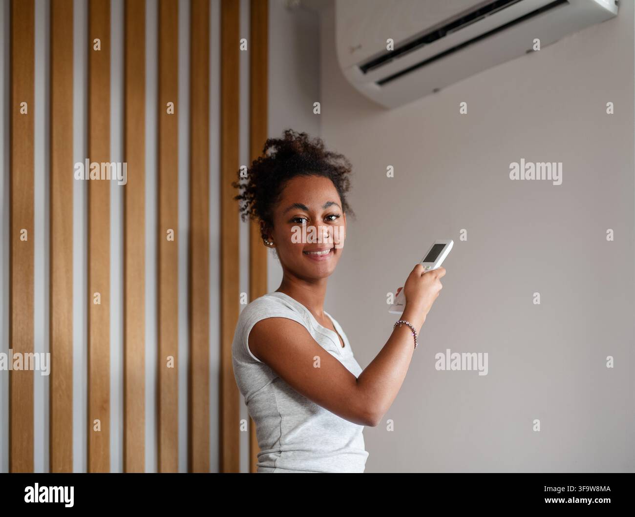 Young woman setting home temperature using air conditioner remote. Stock Photo
