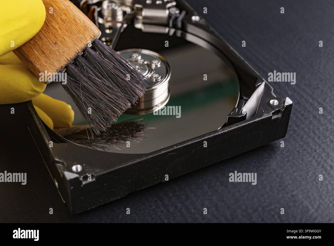 Cleaning the hard disk with a brush. Vacuuming old disk data on your computer. Dark background Stock Photo