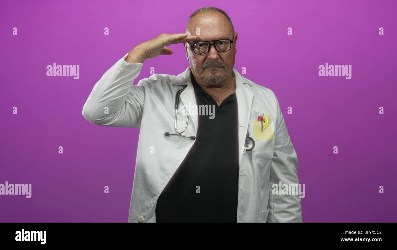 Man doctor in white coat with stethoscope and pens in pocket wearing spectacles salutes with hand to forehead against purple studio backdrop; duty res Stock Photo