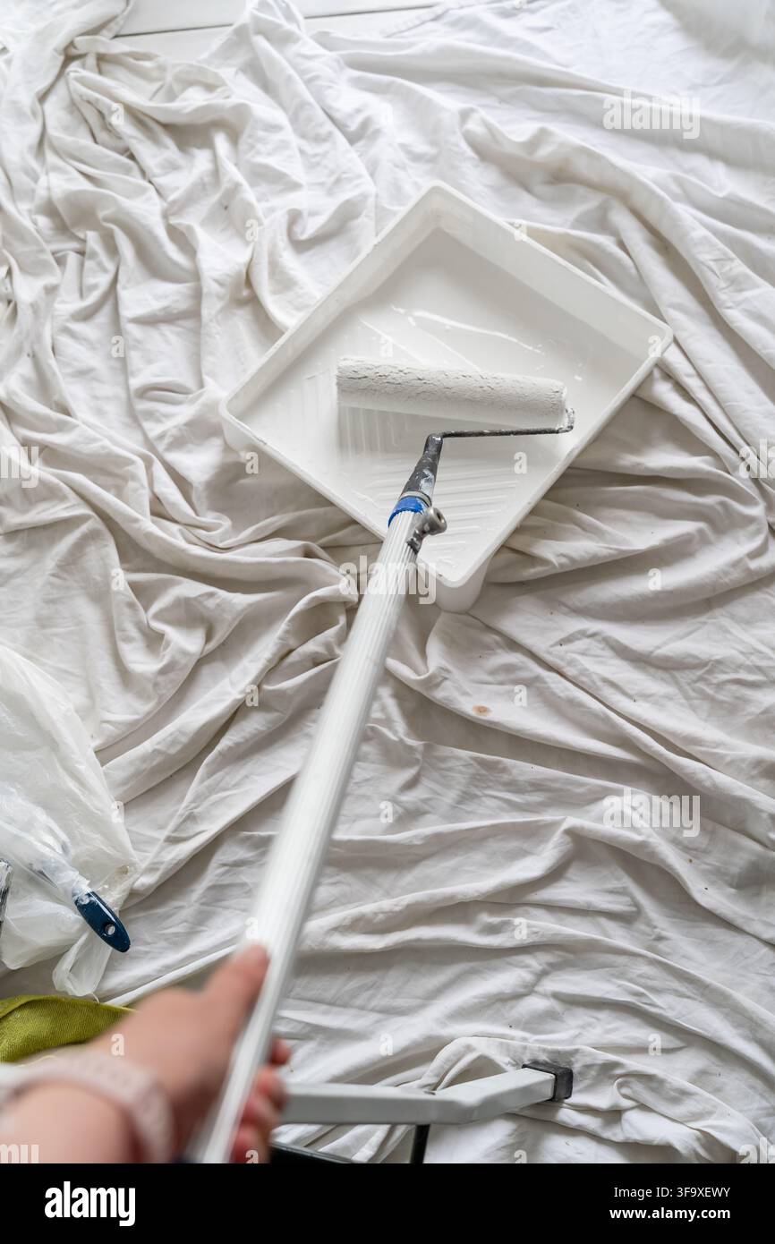 First person view holding a paint roller and tray Stock Photo