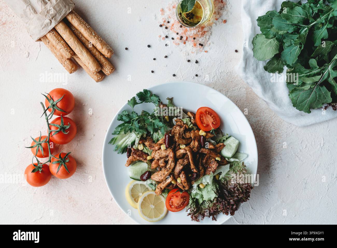 Fresh grilled chicken salad with tomatoes and breadsticks Stock Photo