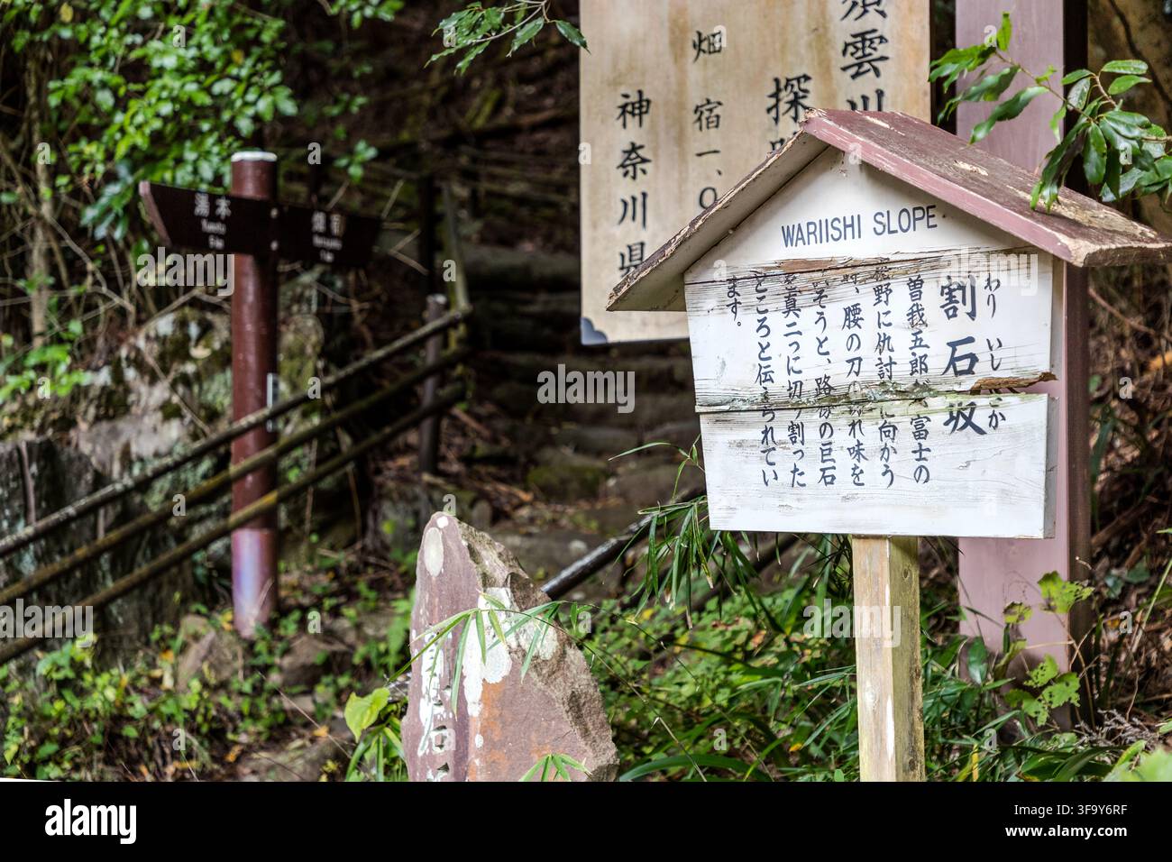 A sign marks Wariishi-zaka (割石坂, "Split Rock Slope") on the Sukumogawa Nature Trail near Hakone, Kanagawa Prefecture, Japan. According to legend, the samurai Soga Gorō Tokimune split a massive boulder here with a single sword strike in 1193 to test his blade's sharpness before avenging his father's murder on the plains of Fuji – part of the Soga brothers' revenge, one of Japan's three great vendettas. Stock Photo