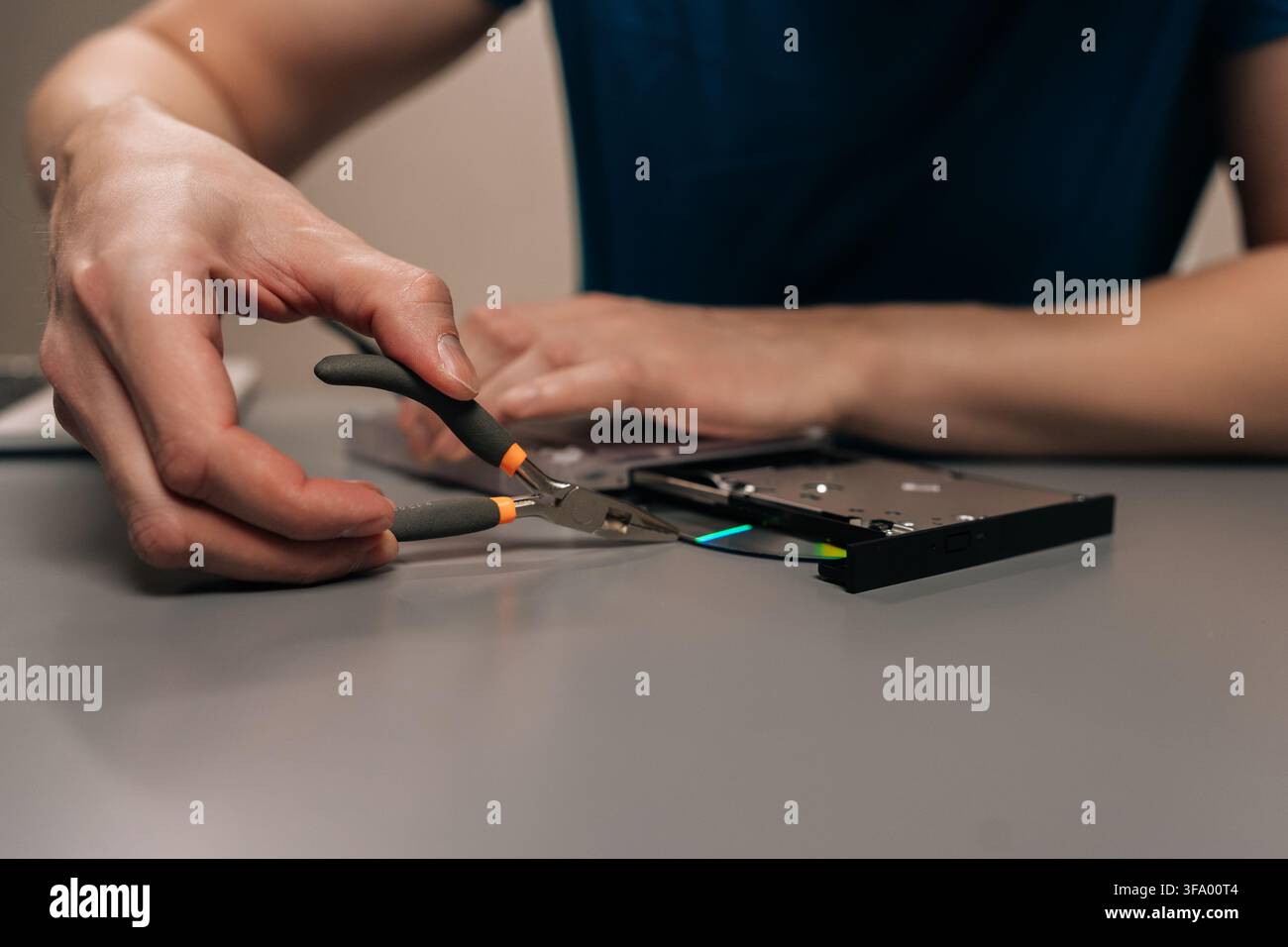 Repairing external optical disc drive using specialized electronic tools, person fixing hardware component, maintenance for portable computer Stock Photo