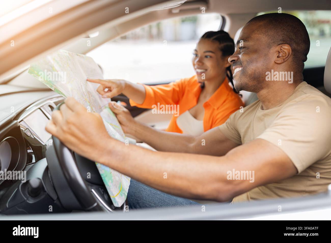 Young Black couple inside car using paper map to plan their route Stock Photo