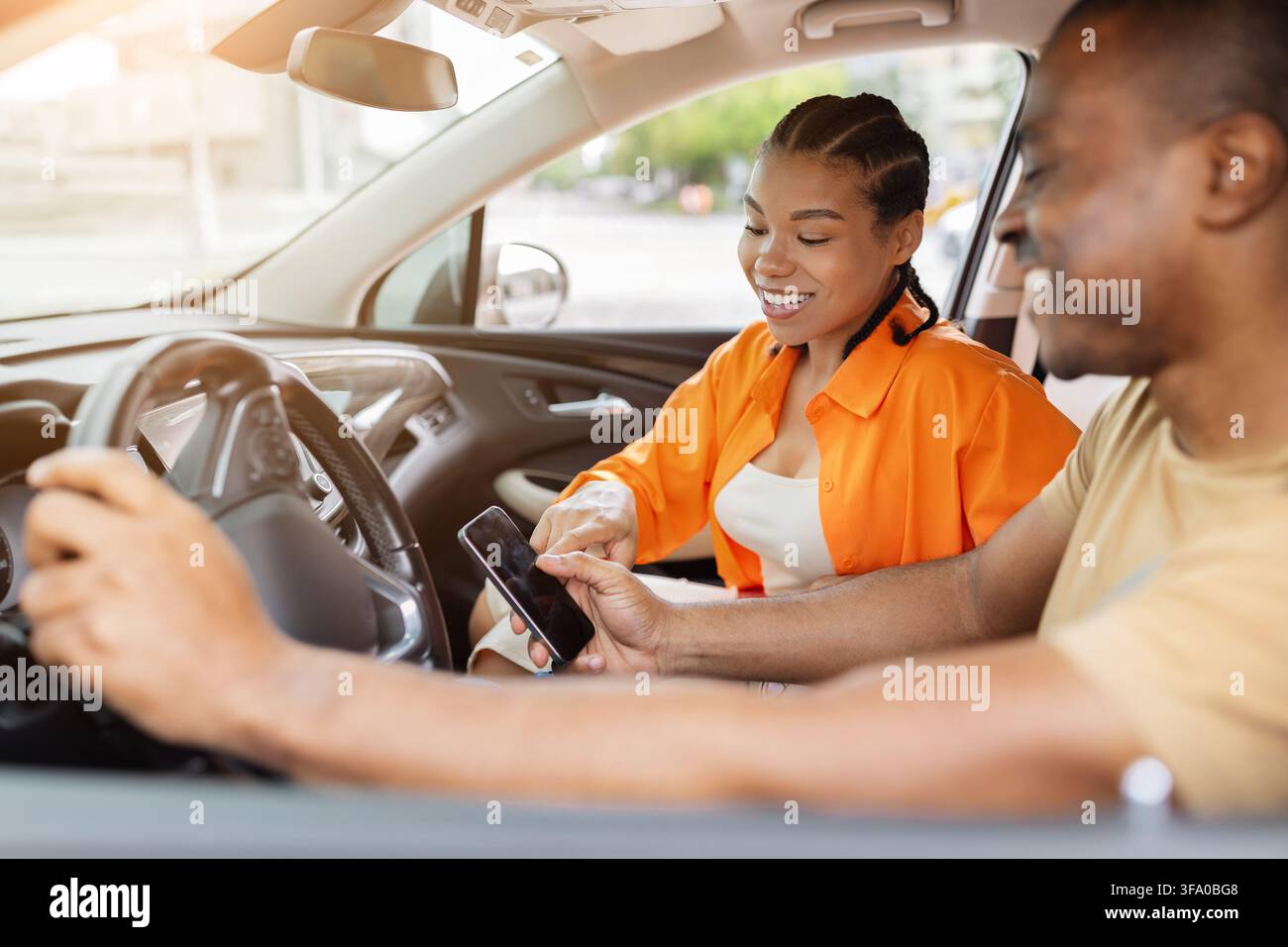 Young Black couple using smartphone together inside car Stock Photo