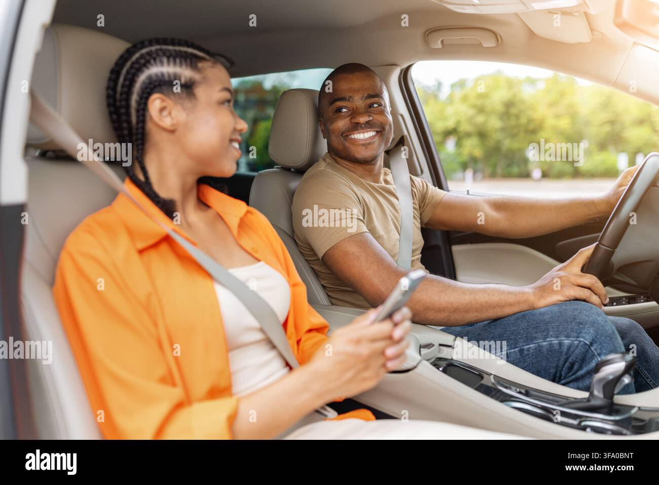 Young Black couple smiling at each other inside modern car Stock Photo