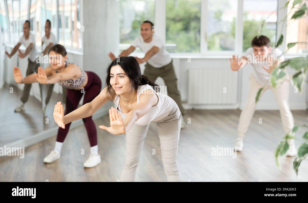 Young brunette warming up with group in dance class Stock Photo