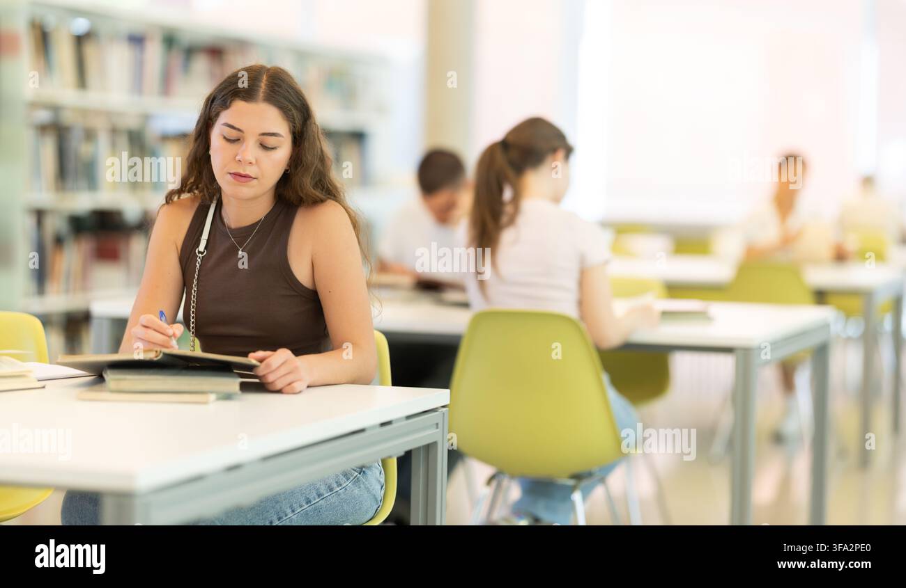Female student sitting at table and writing Stock Photo
