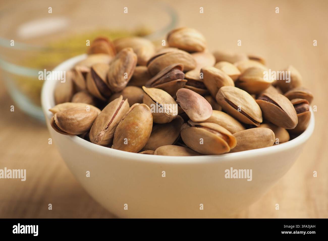 Bowl of pistachio nuts on a wooden table Stock Photo