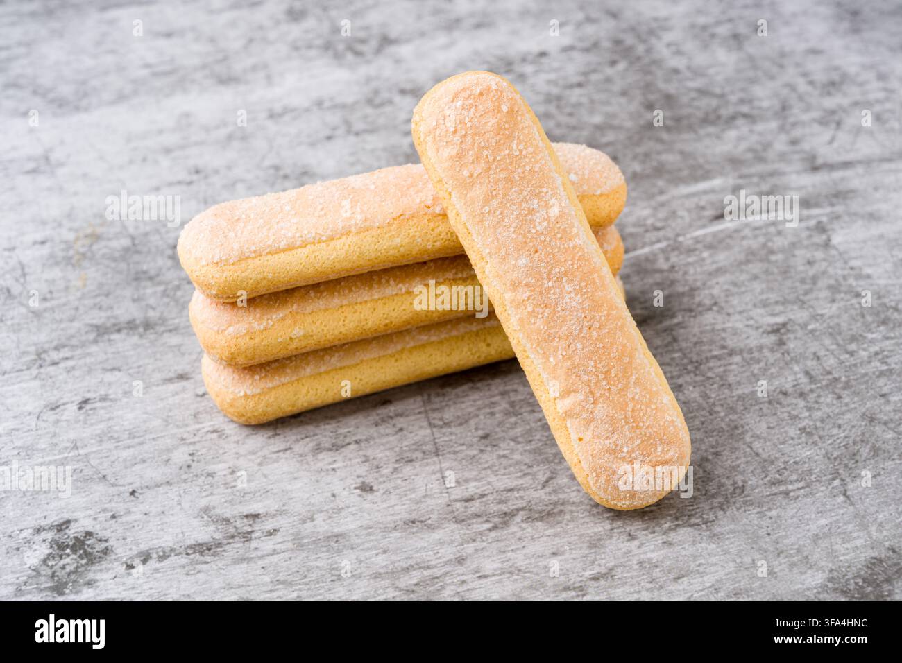Savoiardi biscuits stacked on gray background with one leaning biscuit Stock Photo