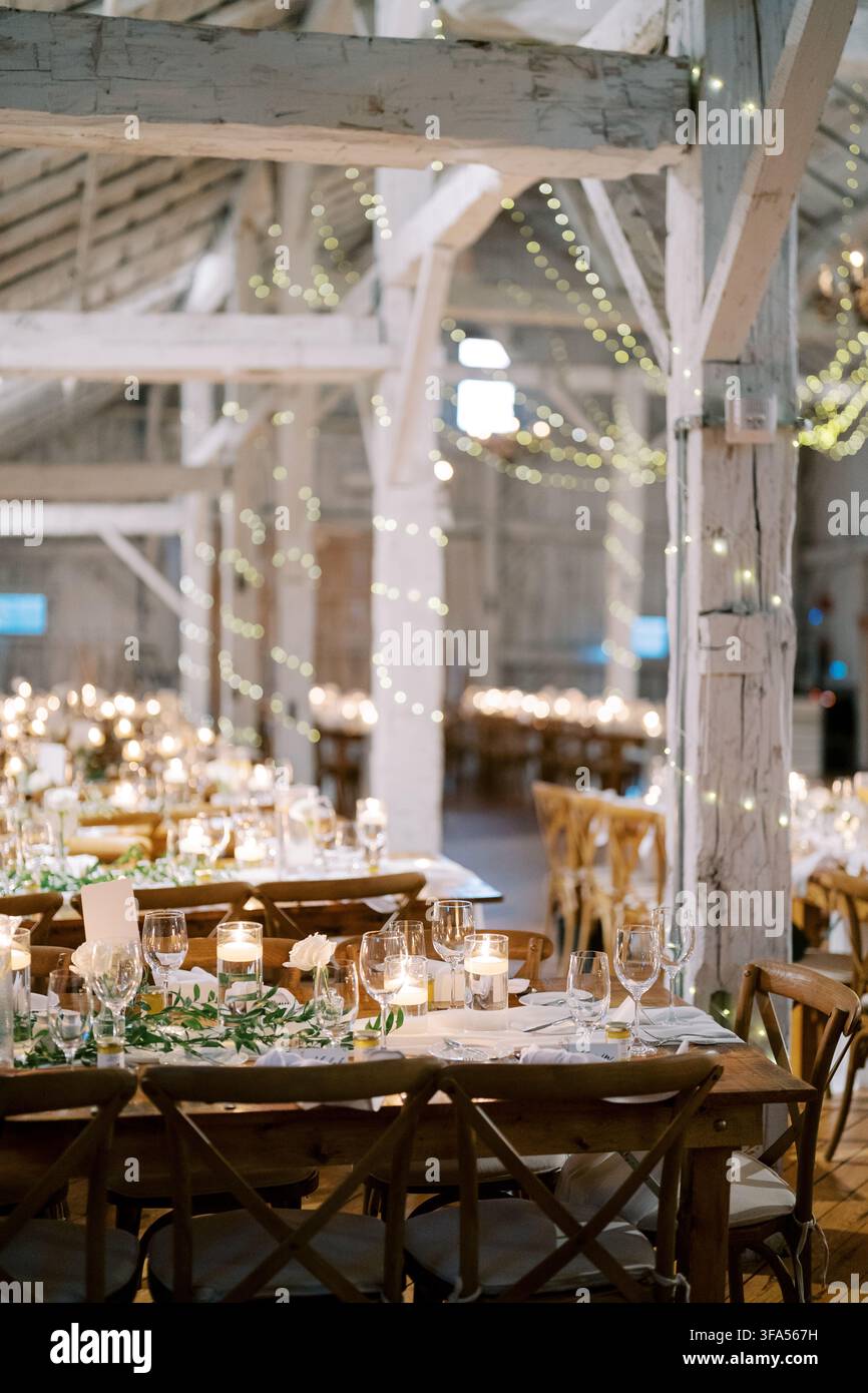 Rustic wedding dinner setup in decorated barn Stock Photo
