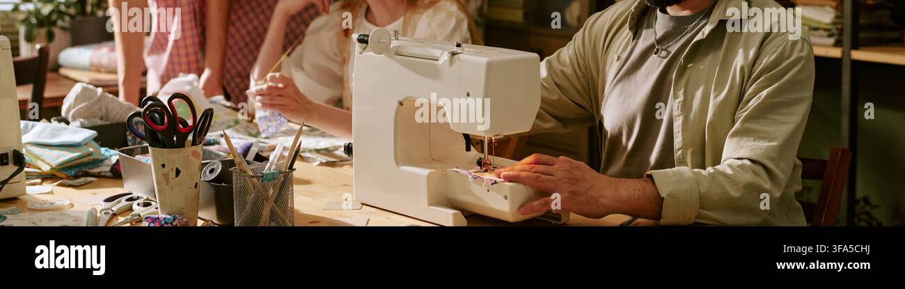 Header of Man Using Sewing Machine in Creative Fashion Workshop Stock Photo