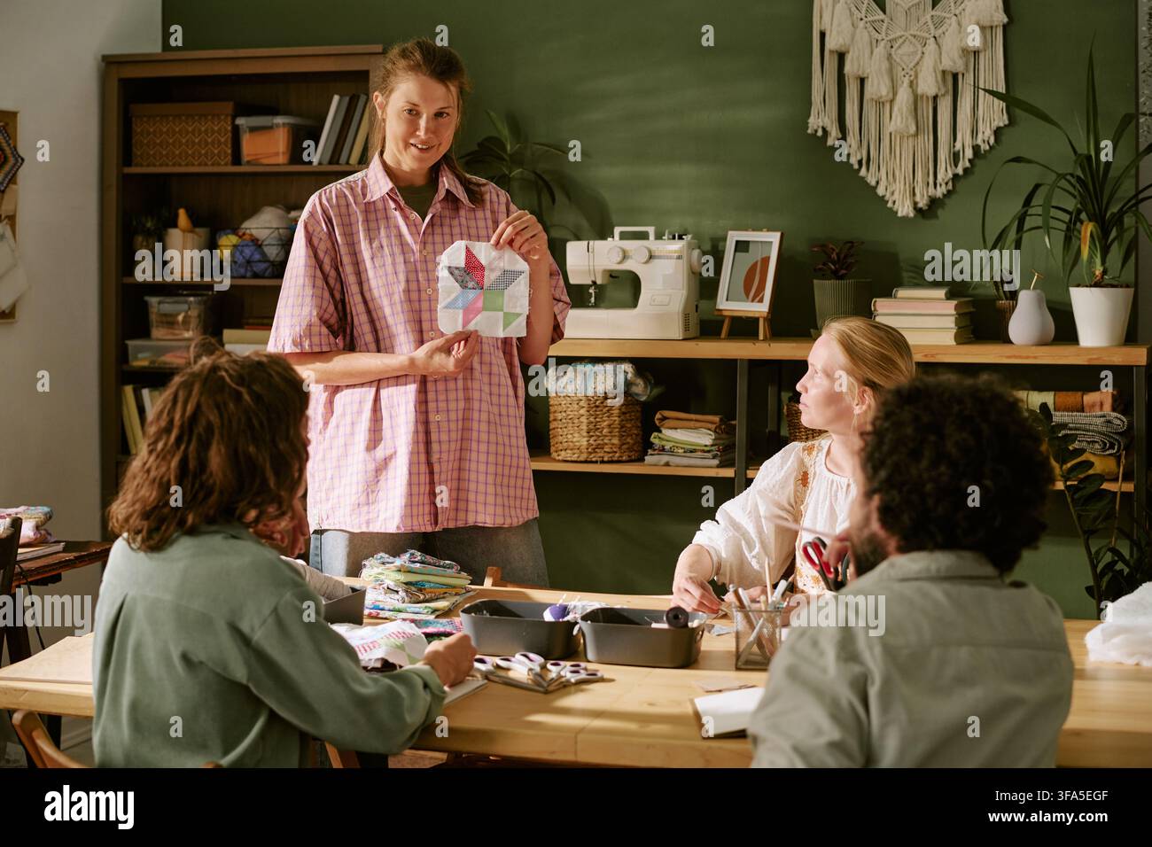 Woman Showing Patchwork Pattern to Students in Sewing Workshop Stock Photo