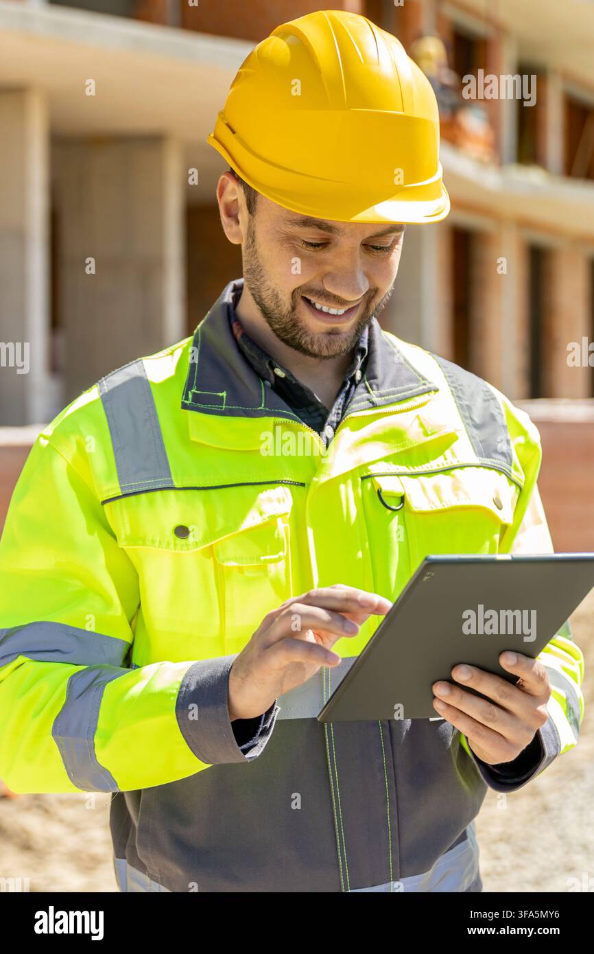 Smiling architectural worker typing on digital tablet computer Stock Photo