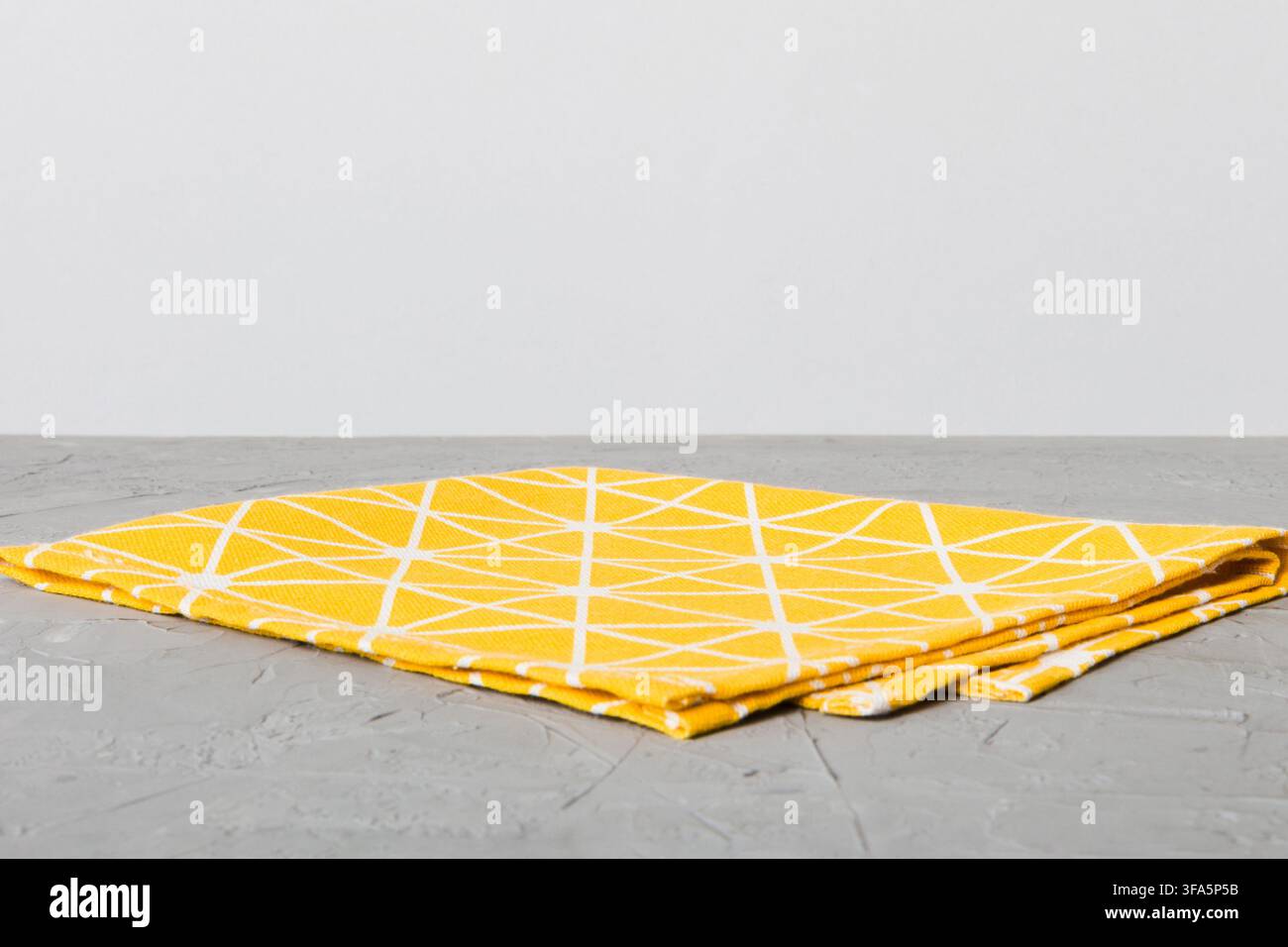 top view with yellow empty kitchen napkin isolated on table background. Folded cloth for mockup with copy space, Flat lay. Minimal style. Stock Photo