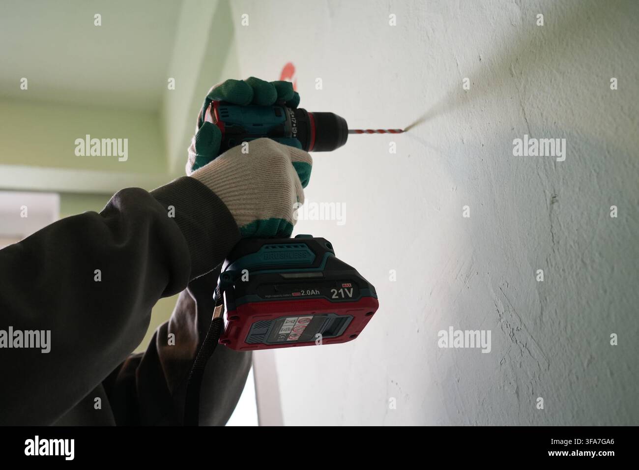 Low angle of hands using brushless cordless drill on wall Stock Photo