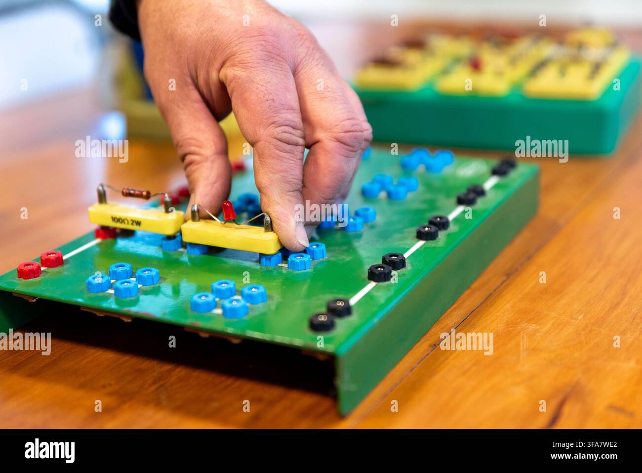 Technician Hands Assembling Electronic Circuit Components on Training Breadboard in Electronics Workshop Stock Photo