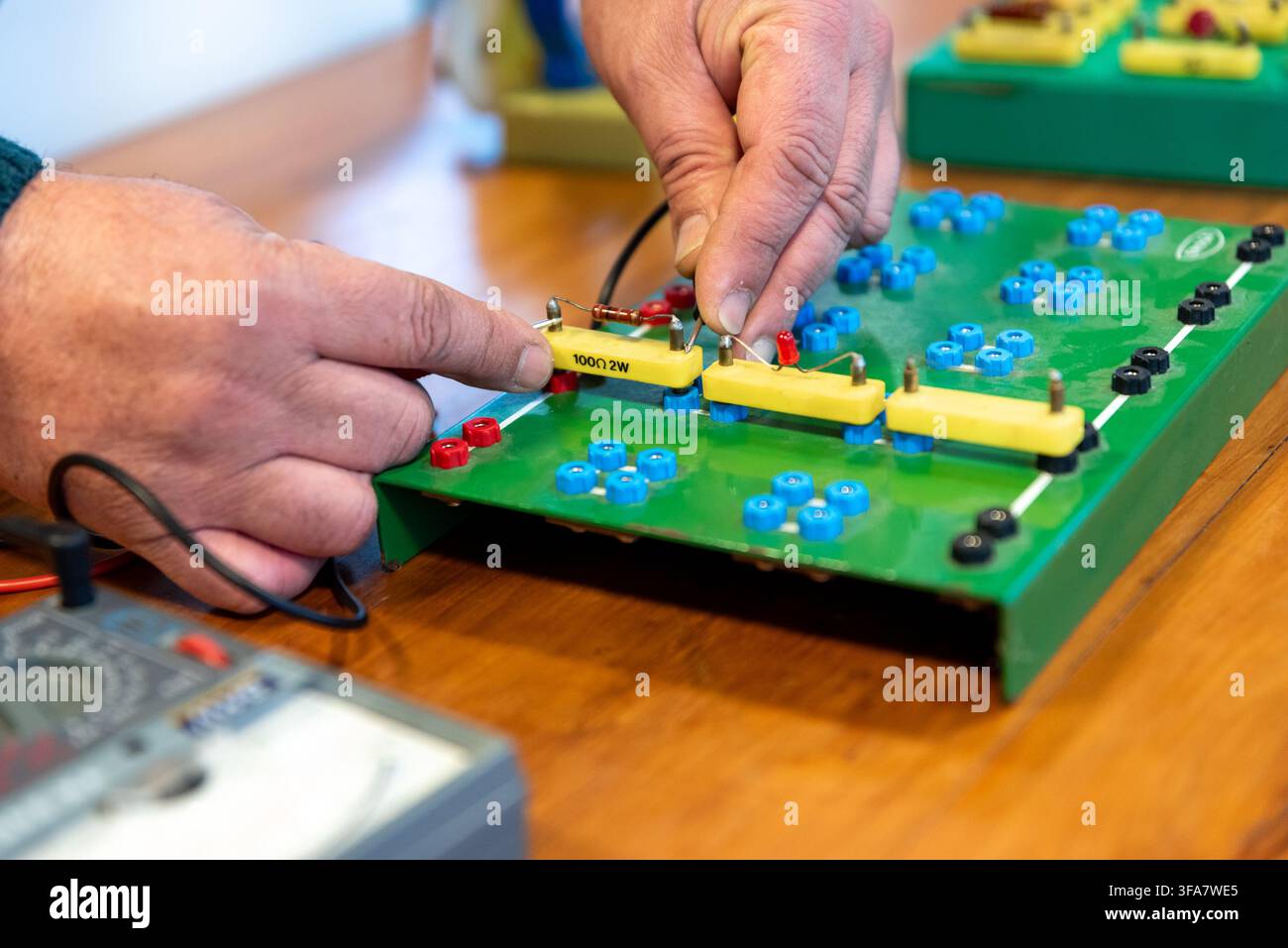 Technician Hands Assembling Electronic Circuit Components on Training Breadboard in Electronics Workshop Stock Photo