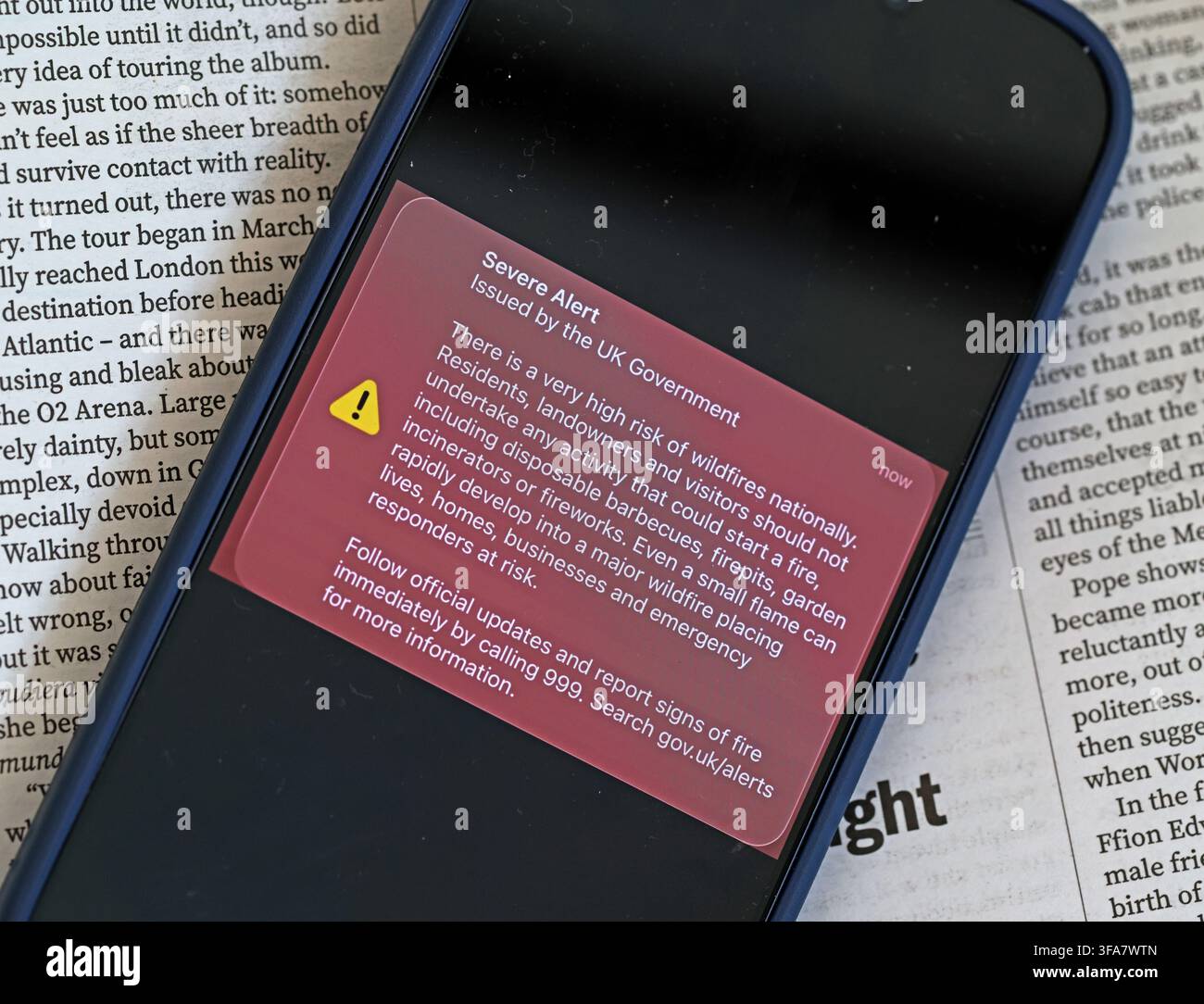 Smartphone showing the 14 August 2026 UK Government wildfire alert, warning the public to avoid barbecues, firepits, fireworks and open flames Stock Photo