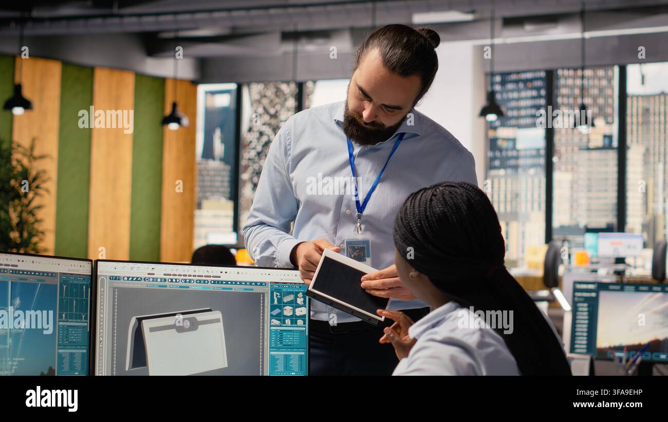 Team of engineers brainstorm upgrades for innovative solar powered device prototype. Research and development office coworkers do trial of portable solar panel gadget to improve efficiency, camera B Stock Photo