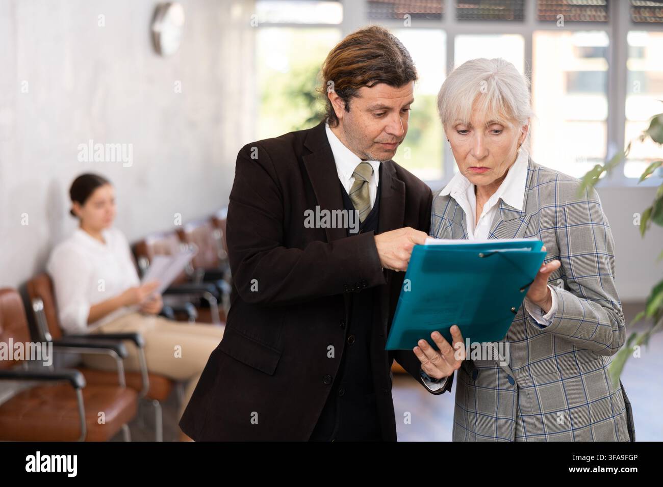 Man discussing working documents with senior female colleague Stock Photo