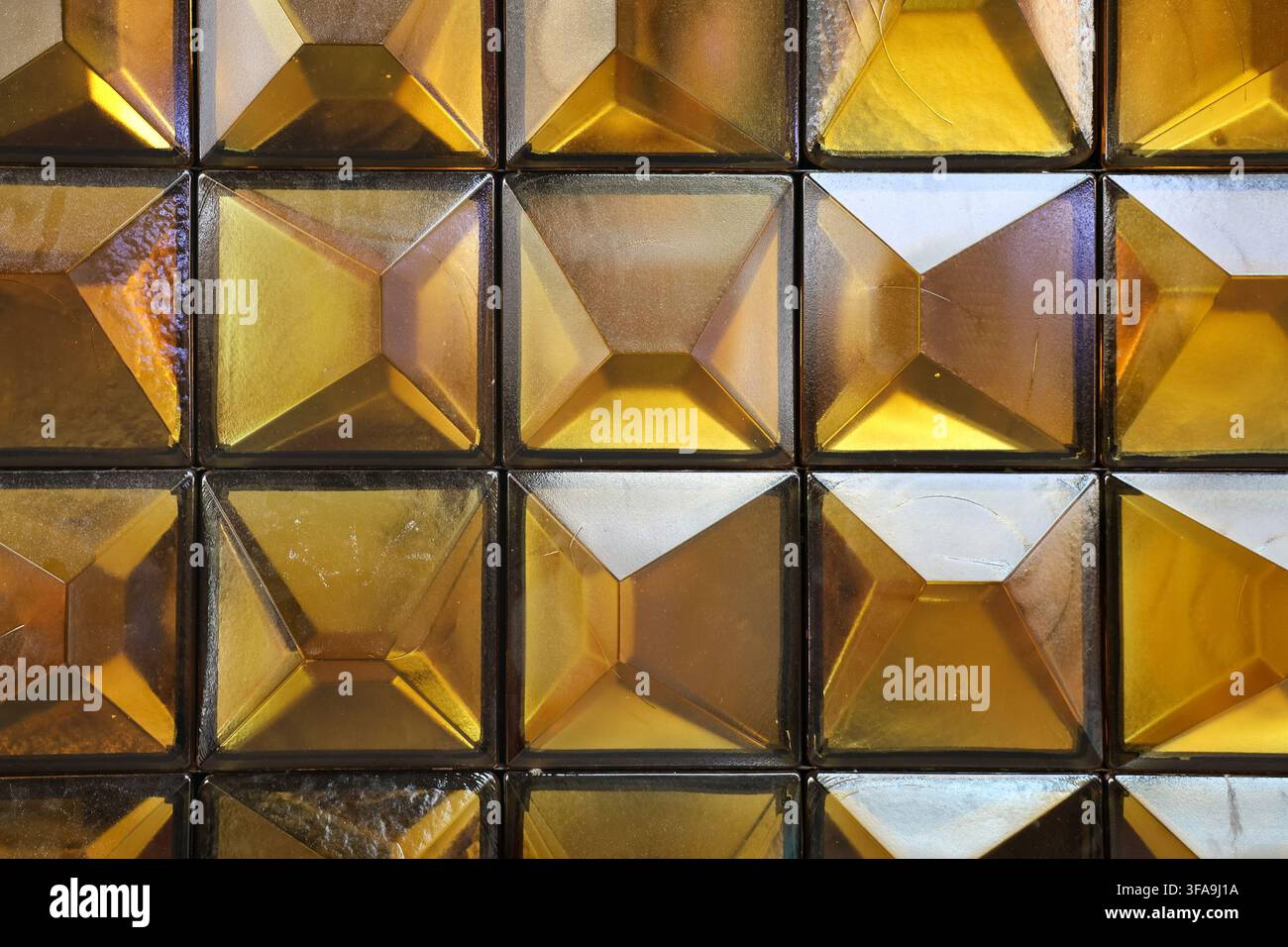 Golden glass squares creating a textured, reflective surface with geometric patterns Stock Photo