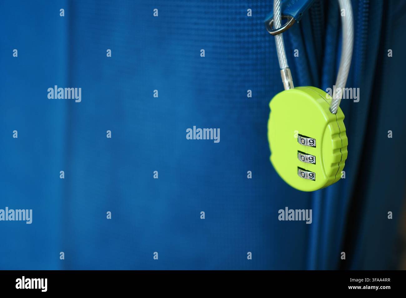 Lock hanging on a blue suitcase by a cable Stock Photo