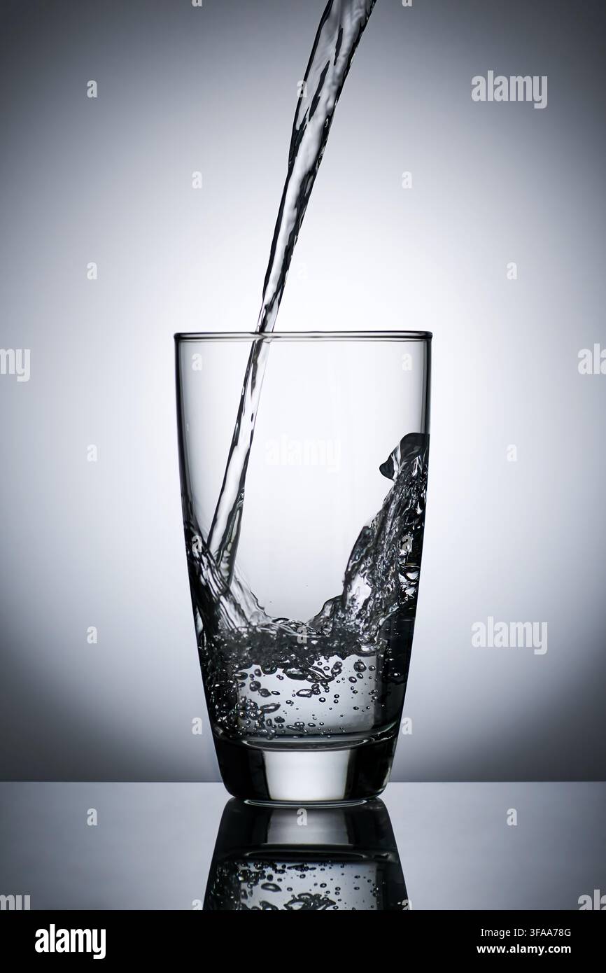 puring refreshment freshness drinking water on clean transperence glass in studio back light Stock Photo