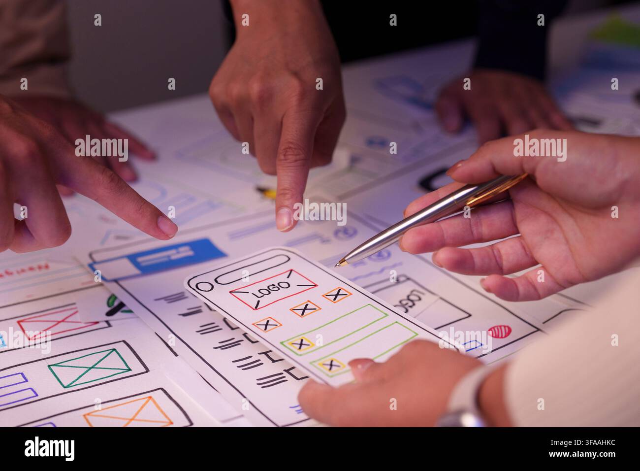 Designers pointing at mobile application wireframe layout during UX UI brainstorming session Stock Photo