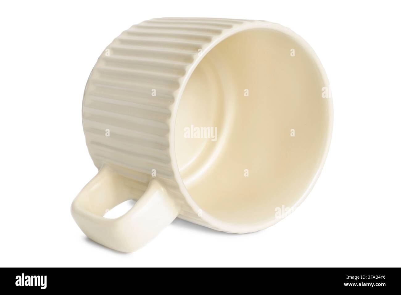 Empty ribbed ceramic beige cup lying on white background Stock Photo