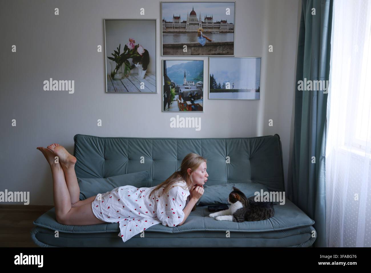 Woman relaxing on couch and interacting with her cat, showing affection and companionship at home. Stock Photo