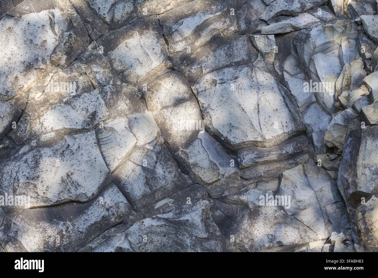 Rock surface forming a natural stone background with cracks and textured patterns. Stock Photo